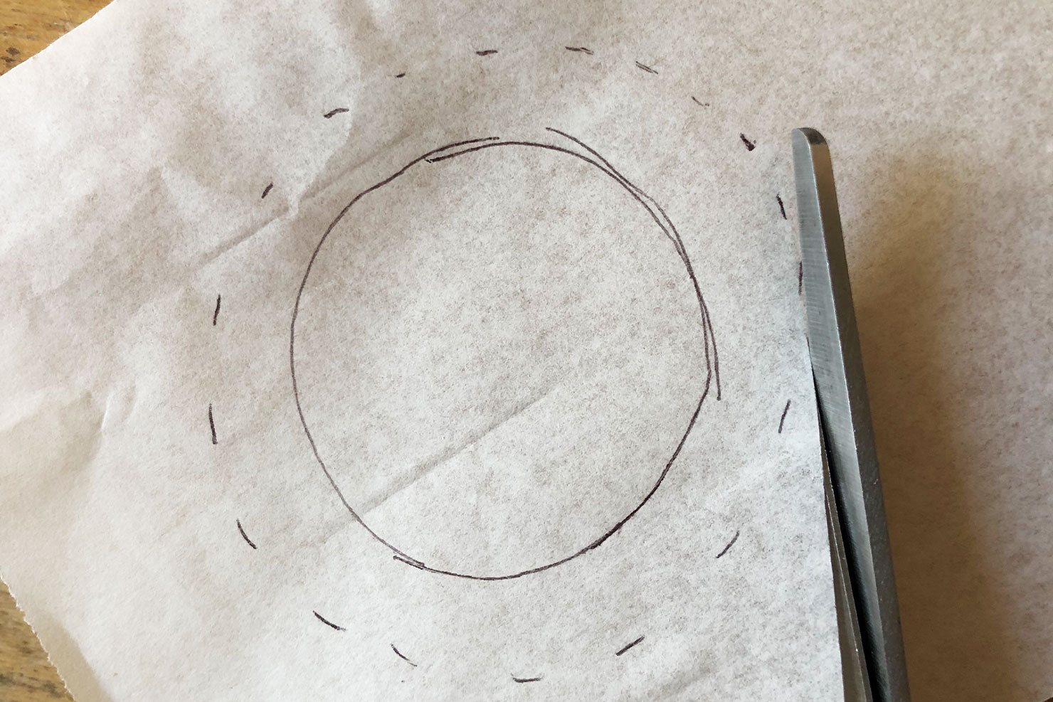 Ein gemalter Kreis auf Butterbrotpapier wird ausgeschnitten.
