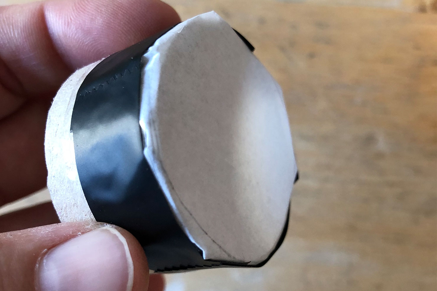 Ein Kreis aus Butterbrotpapier wird mit Isolierband auf eine Klorolle geklebt.