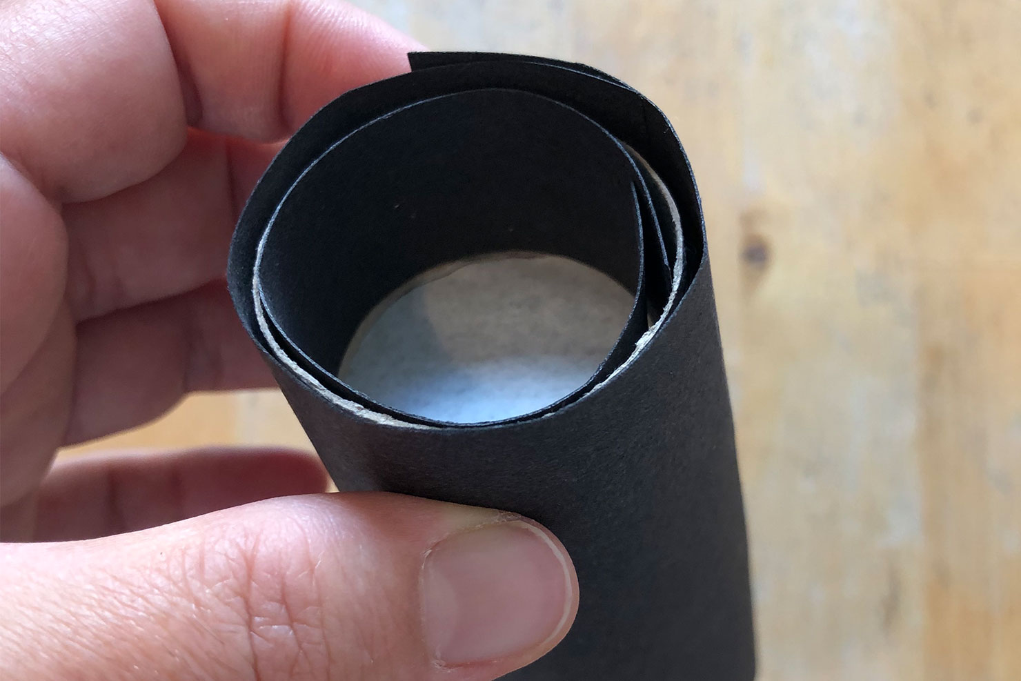 Eine Rolle Tonpapier wird um die gebastelte Lochkamerakappe geklebt.