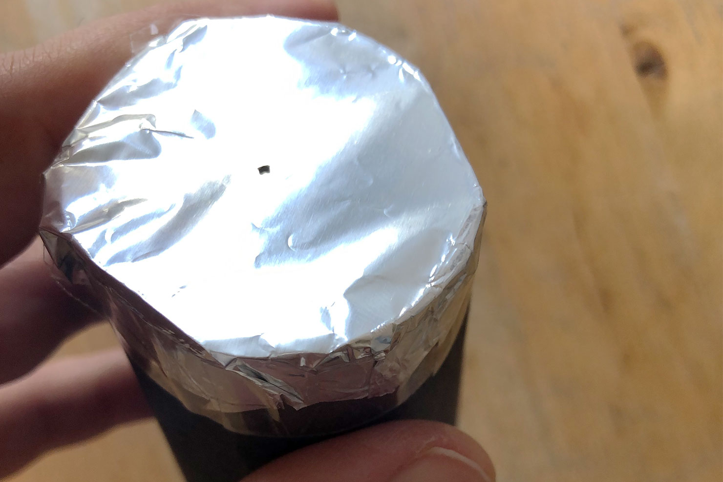 In die Alufolie der gebastelten Lochkamera wird ein Loch gepiekst.