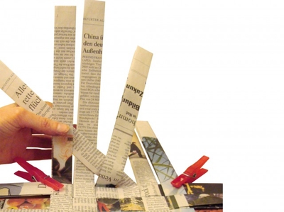 Zwei Hände flechten Papierstreifen