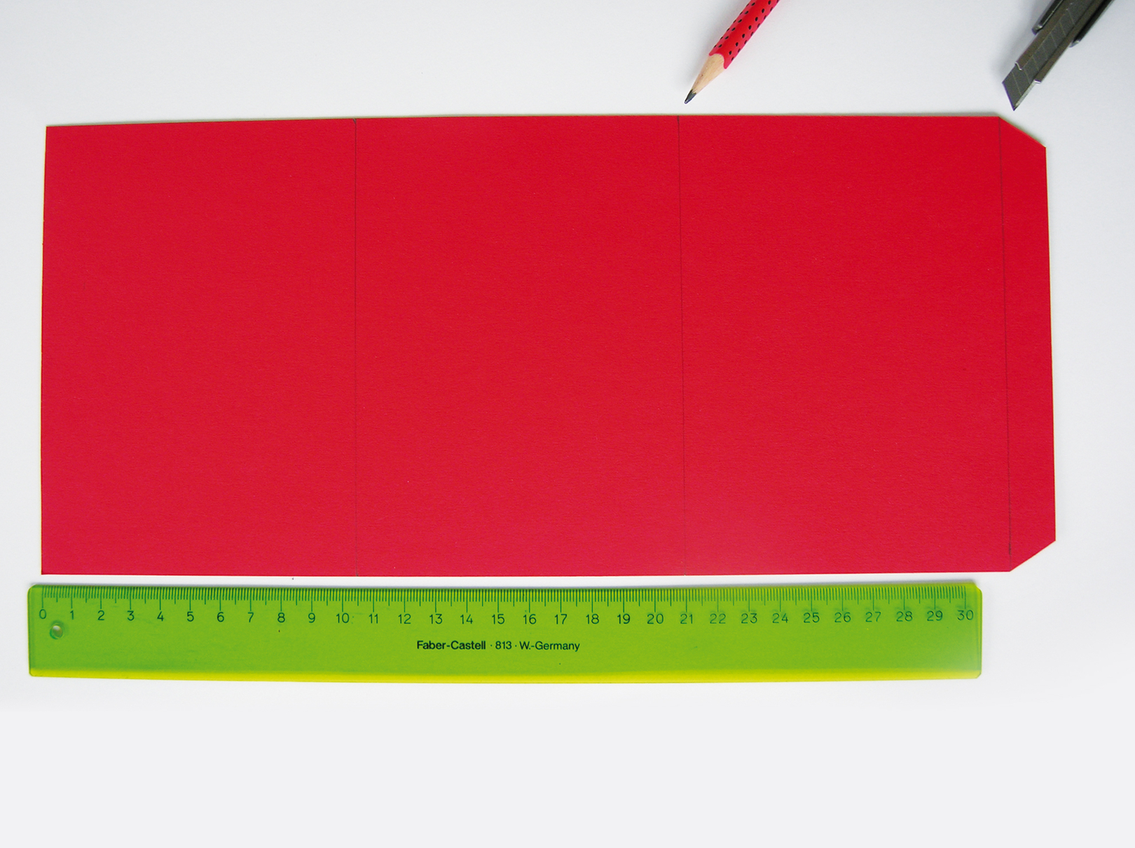 Rotes Papier mit Schere und schwarzer Drachenform für Windlicht.