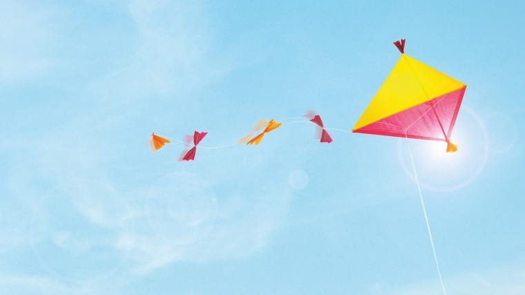 Bunter Drachen fliegen bei blauem Himmel mit kleinen Wölkchen